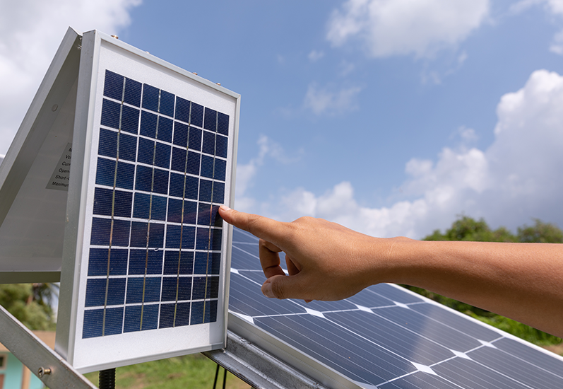Solar technician inspecting a solar power system inverter for maintenance and efficiency.